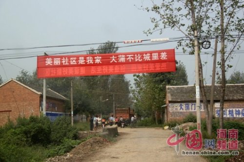 死者的家屬在村口迎接前來吊唁的親友，紅色的橫幅看上去更具諷刺意味。