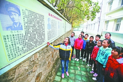 上圖：學校文化墻前，小講解員講述開國將軍杜義德的故事。記者何曉剛 攝