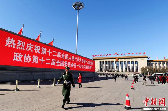 3月4日，北京晴空萬里，武警從北京天安門廣場大型顯示屏前走過。3月5日上午，十二屆全國人大一次會議將隆重開幕。中新社發(fā) 劉忠俊 攝