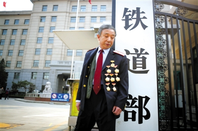 3月14日，鐵道部大門口，一位胸前掛著多枚勛章的鐵道部老職工與鐵道部牌子合影。 新京報記者 侯少卿 攝
