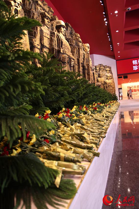 紀(jì)念館門廳的《銅墻鐵壁》雕塑墻，和人們獻(xiàn)上的花。邱越攝